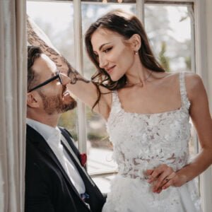 Blossom is a modern and elegant wedding gown featuring delicate 3D-floral design, flowing silhouette with a chapel length train, and intricate lace details on the bodice.